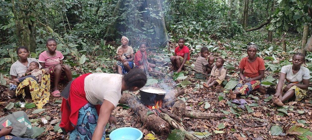 a group of people around a campfire eating and resting